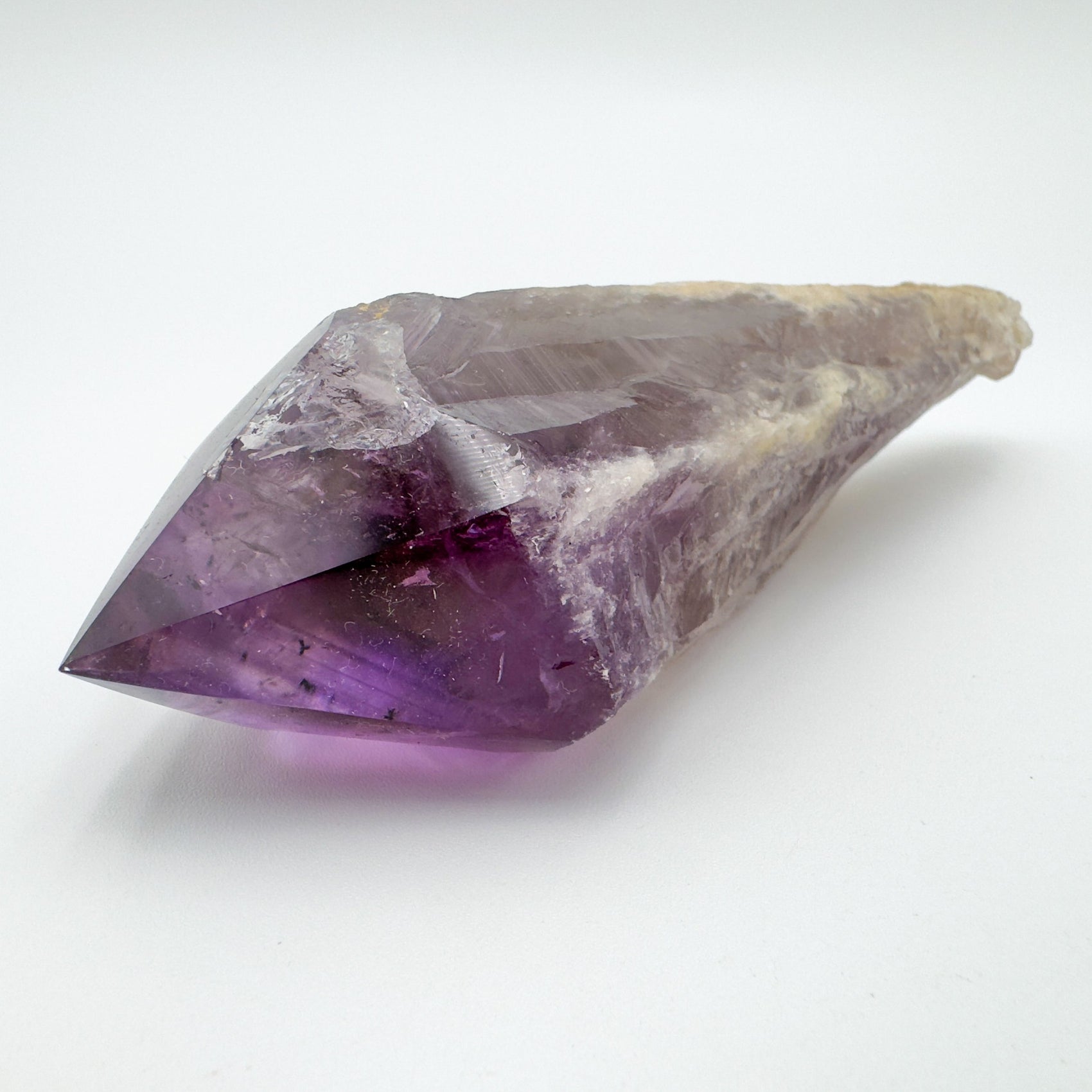 Palm-scale view of a Amethyst polished point held against natural backdrop.