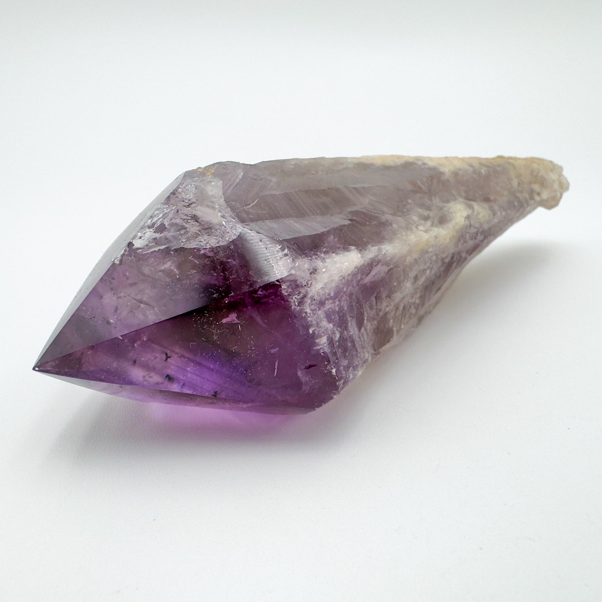 Palm-scale view of a Amethyst polished point held against natural backdrop.