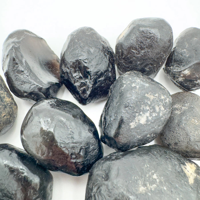 Hand-held view of a single Apache Tear raw stone United States-sourced, sourced from Arizona, United States.