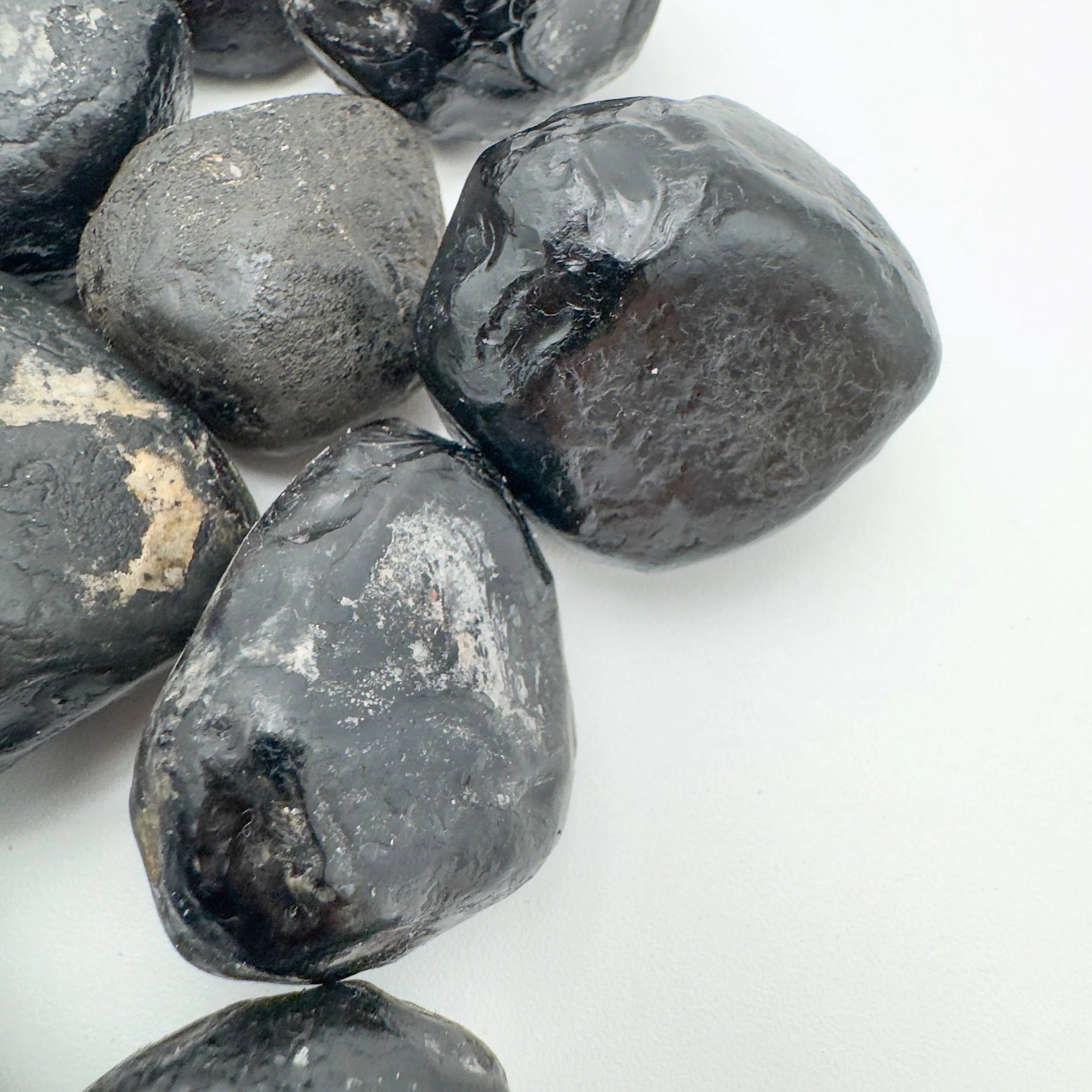 Set against a soft backdrop is an Apache Tear stone, shown at hand scale.