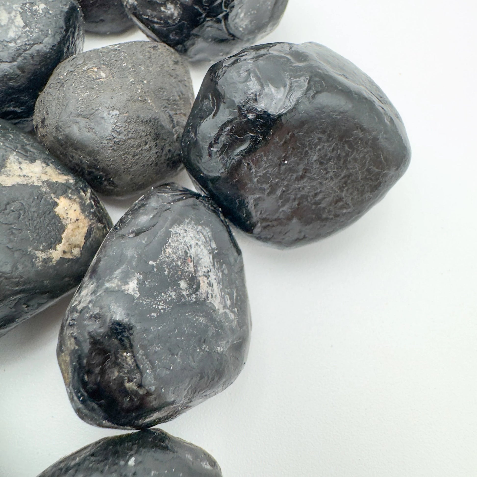 Set against a soft backdrop is an Apache Tear stone, shown at hand scale.