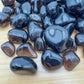 Side angle of Apache Tear tumbled stone, showing characteristic color, sourced from Arizona, United States.