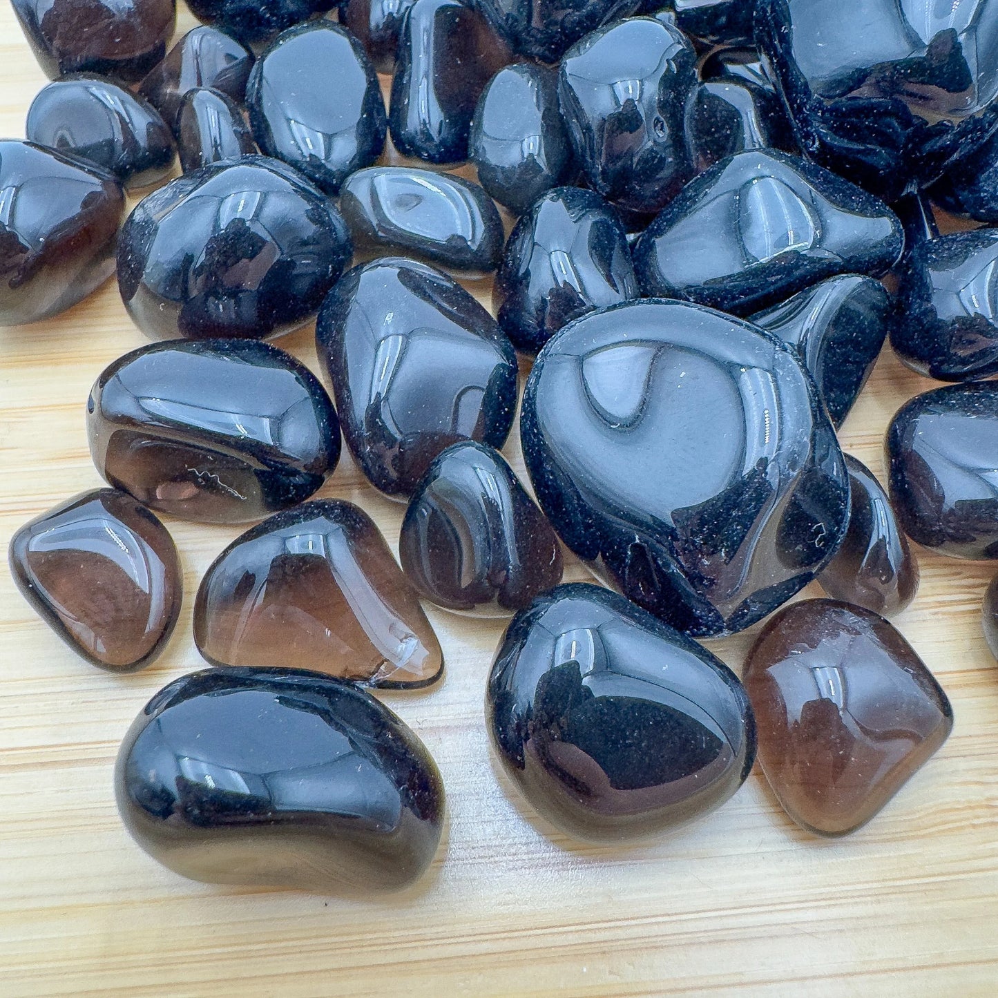 Side angle of Apache Tear tumbled stone, showing characteristic color, sourced from Arizona, United States.