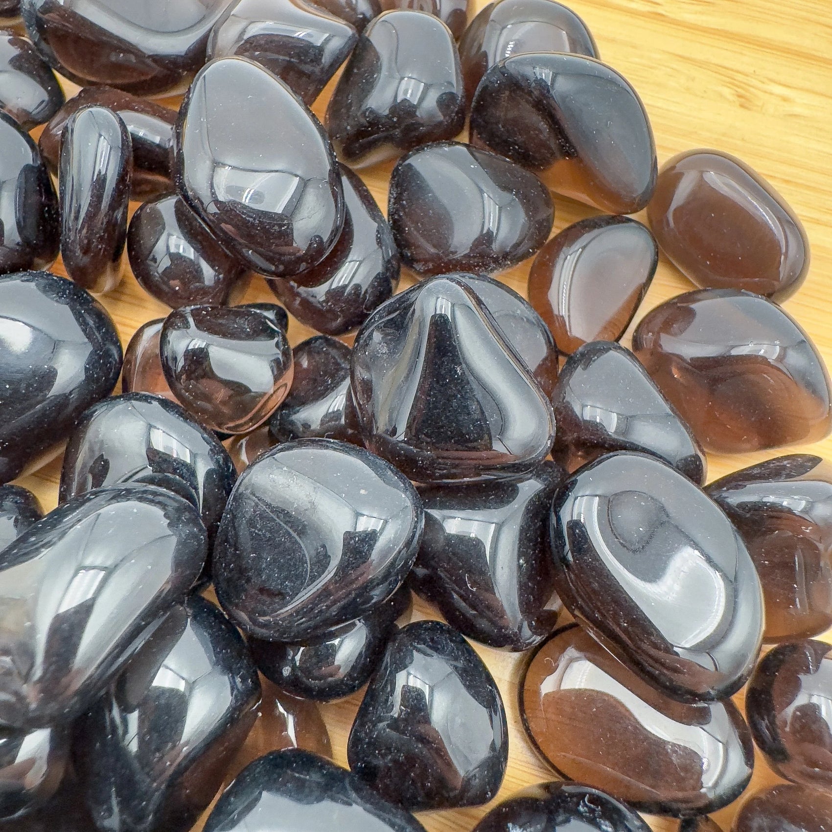 Color detail of Apache Tear tumbled stone, sourced from United States, often kept for Grounding and Protection.