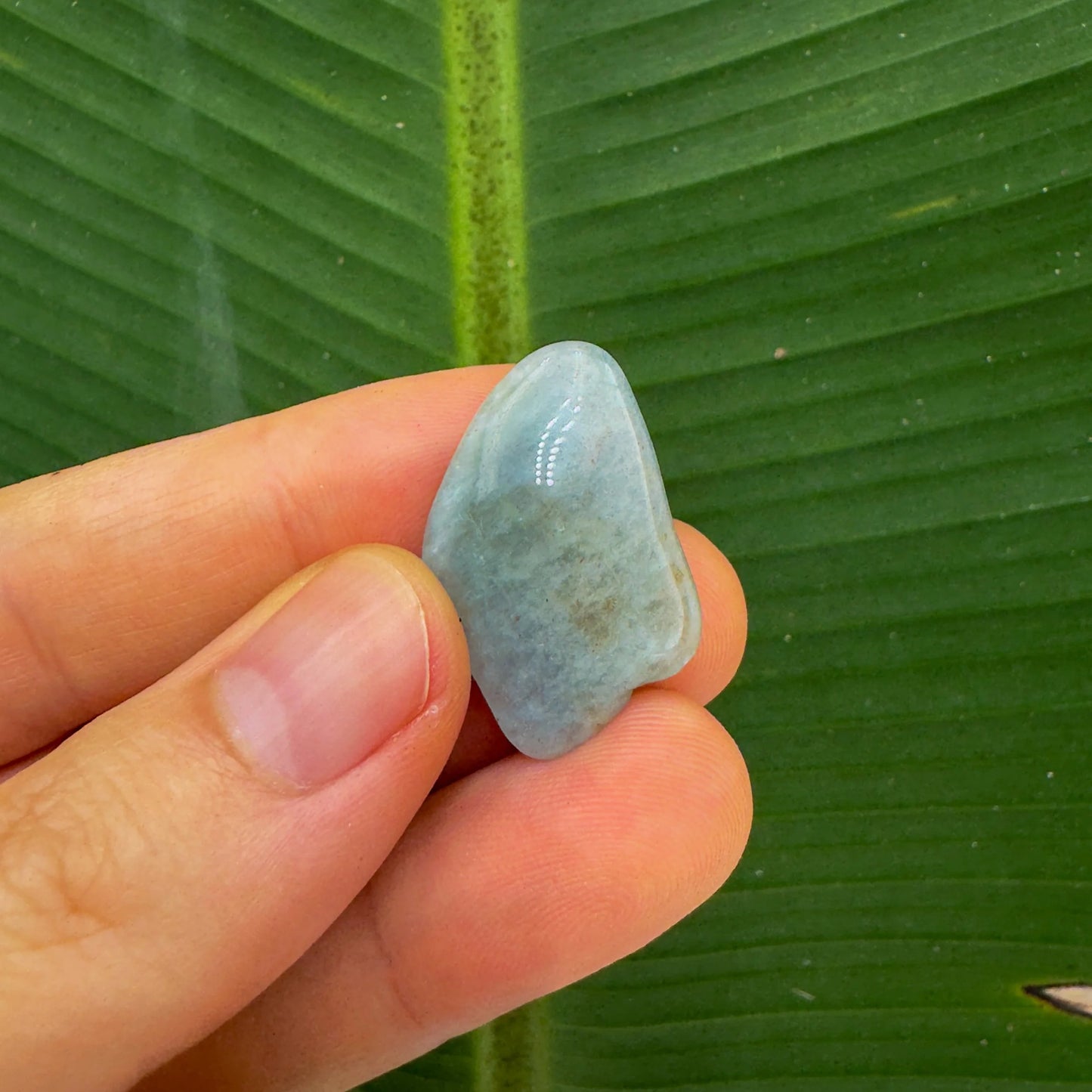 Three-quarter view of Aquamarine tumbled stone, from Minas Gerais, Brazil, captured against a quiet backdrop.