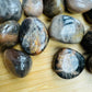 Palm-scale view of a Black Moonstone tumbled stone, Madagascar-sourced, Madagascar-sourced.