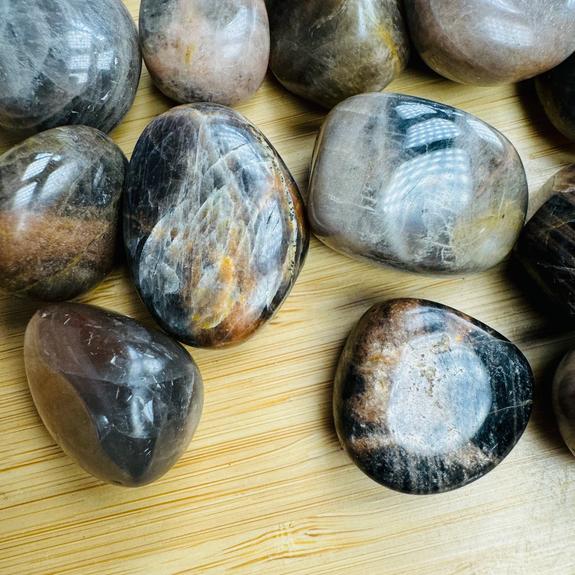 Palm-scale view of a Black Moonstone tumbled stone, Madagascar-sourced, Madagascar-sourced.