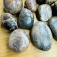 Alternate side of Grade AA Black Moonstone tumbled stone, showing color depth.