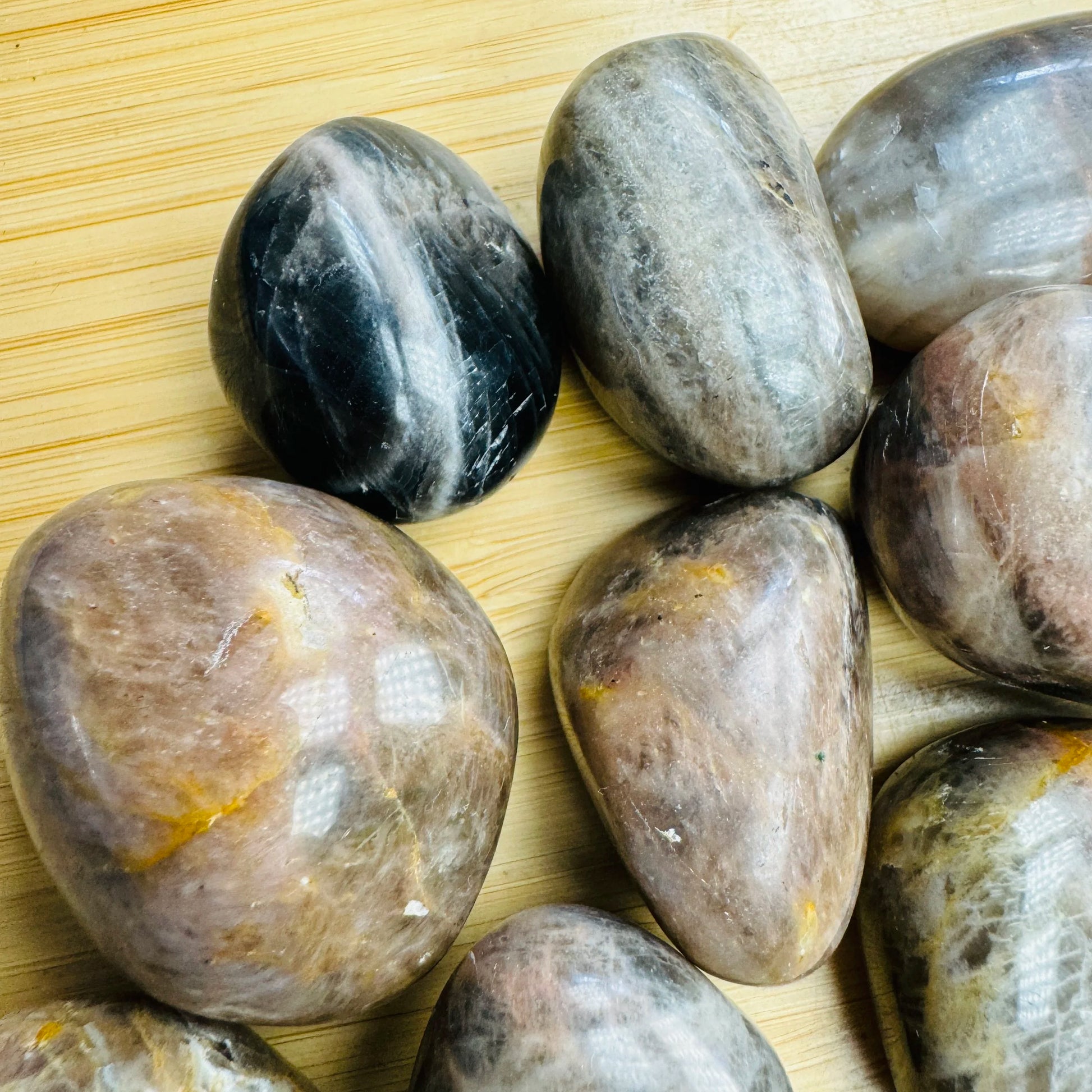 Sideways view of Black Moonstone tumbled stone, showing color depth.