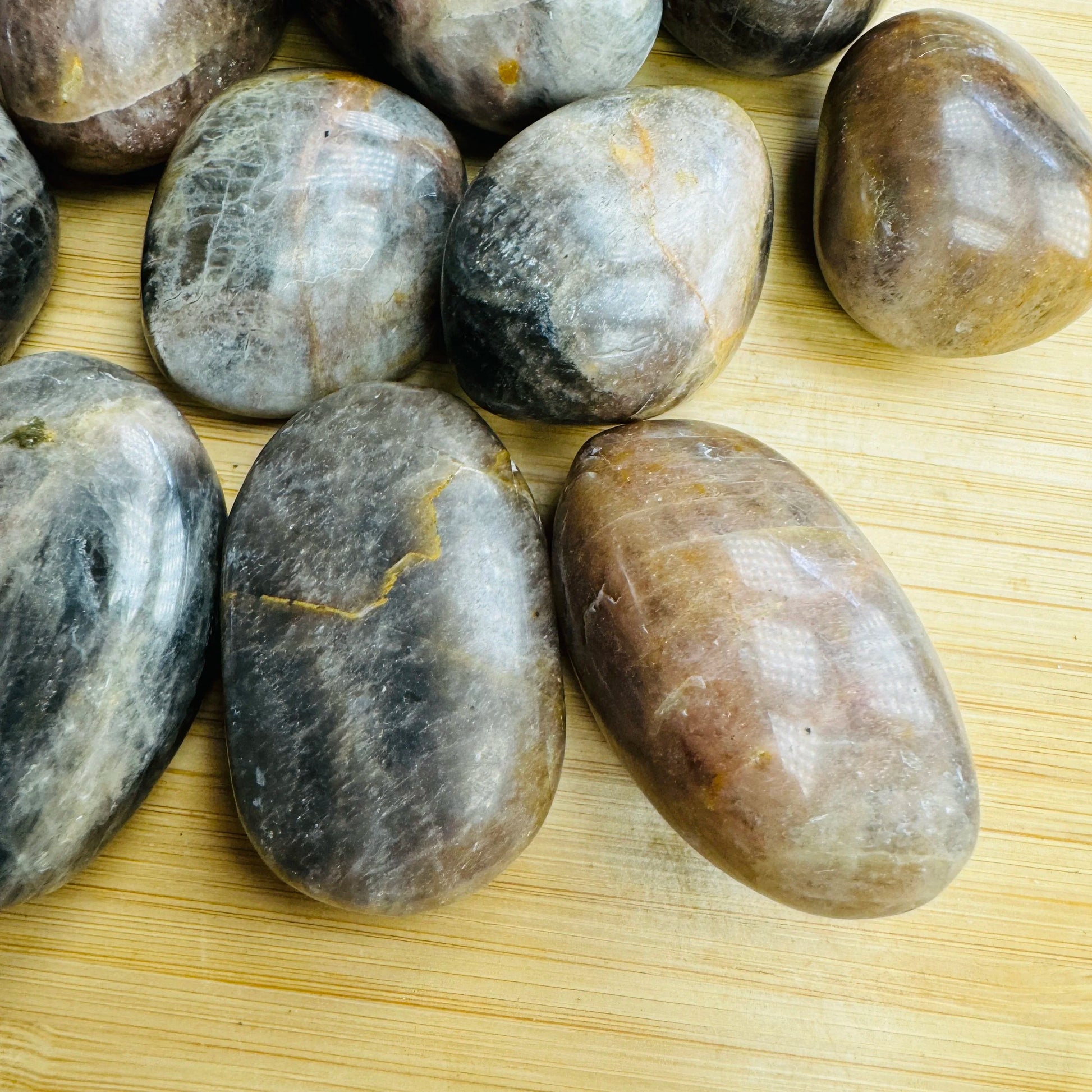 Top-side view of Grade AA Black Moonstone tumbled stone, showing glassy finish, kept close for Grounding.