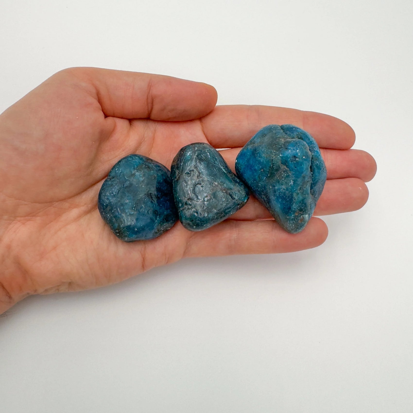 Tabletop view of Apatite tumbled stone, set to give a sense of weight.