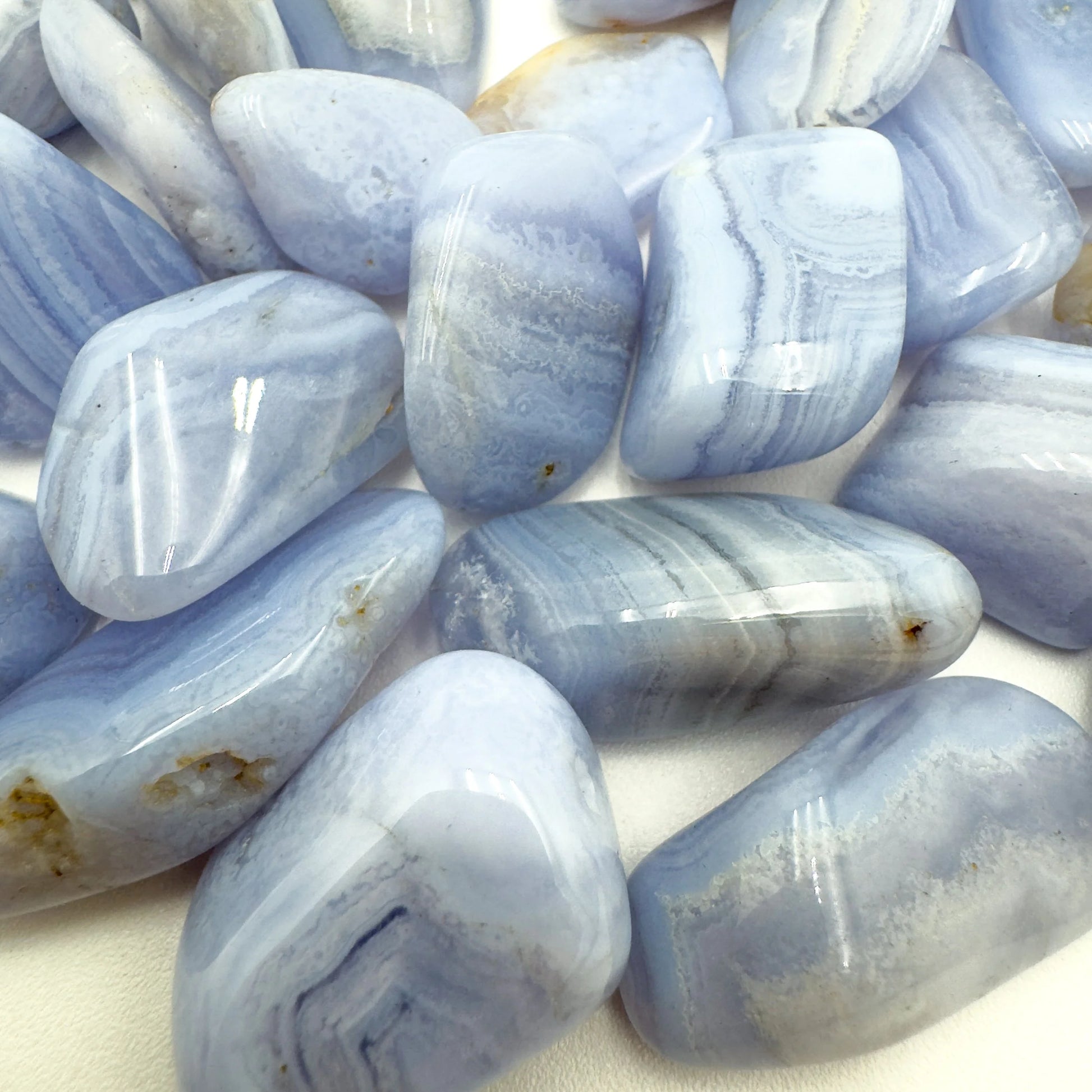 Sideways view of Blue Lace Agate tumbled stone, showing natural inclusions.