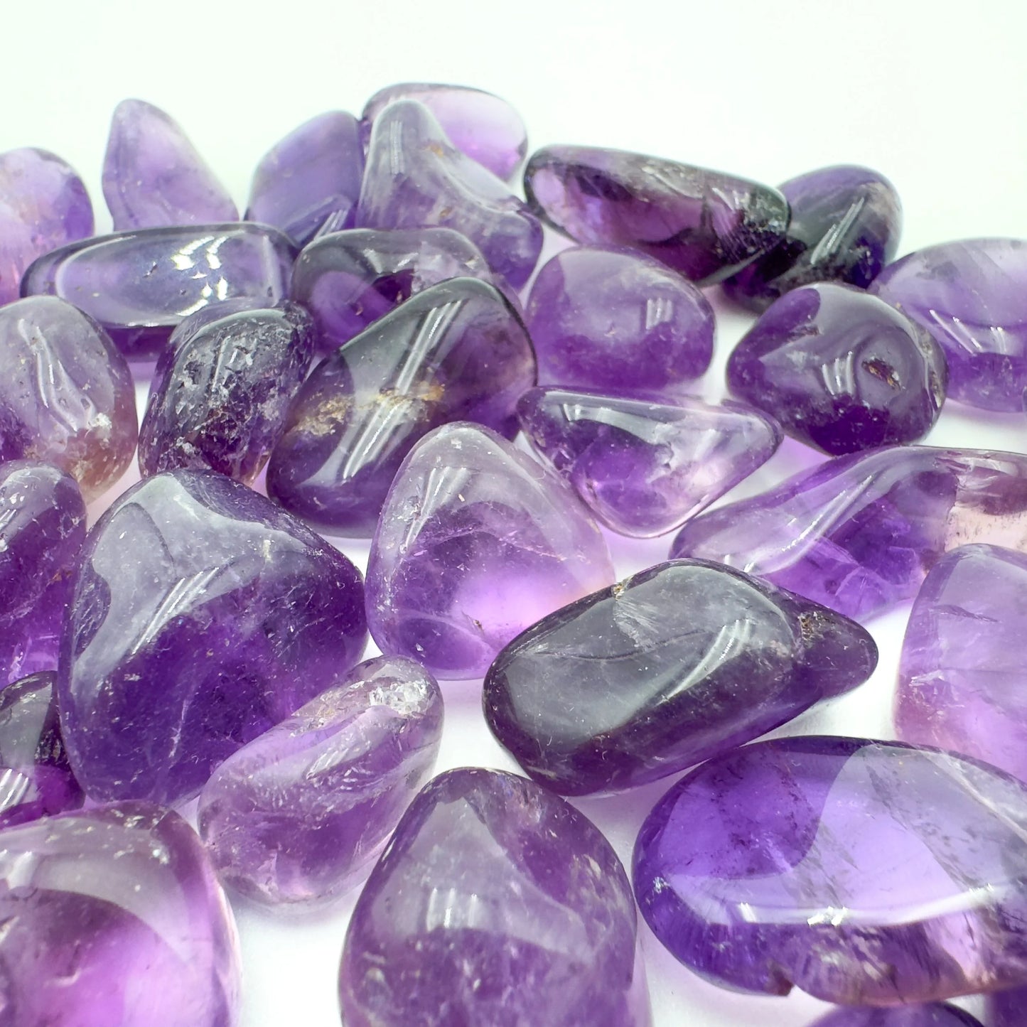 In-hand view of a Amethyst tumbled stone, from Brazil.