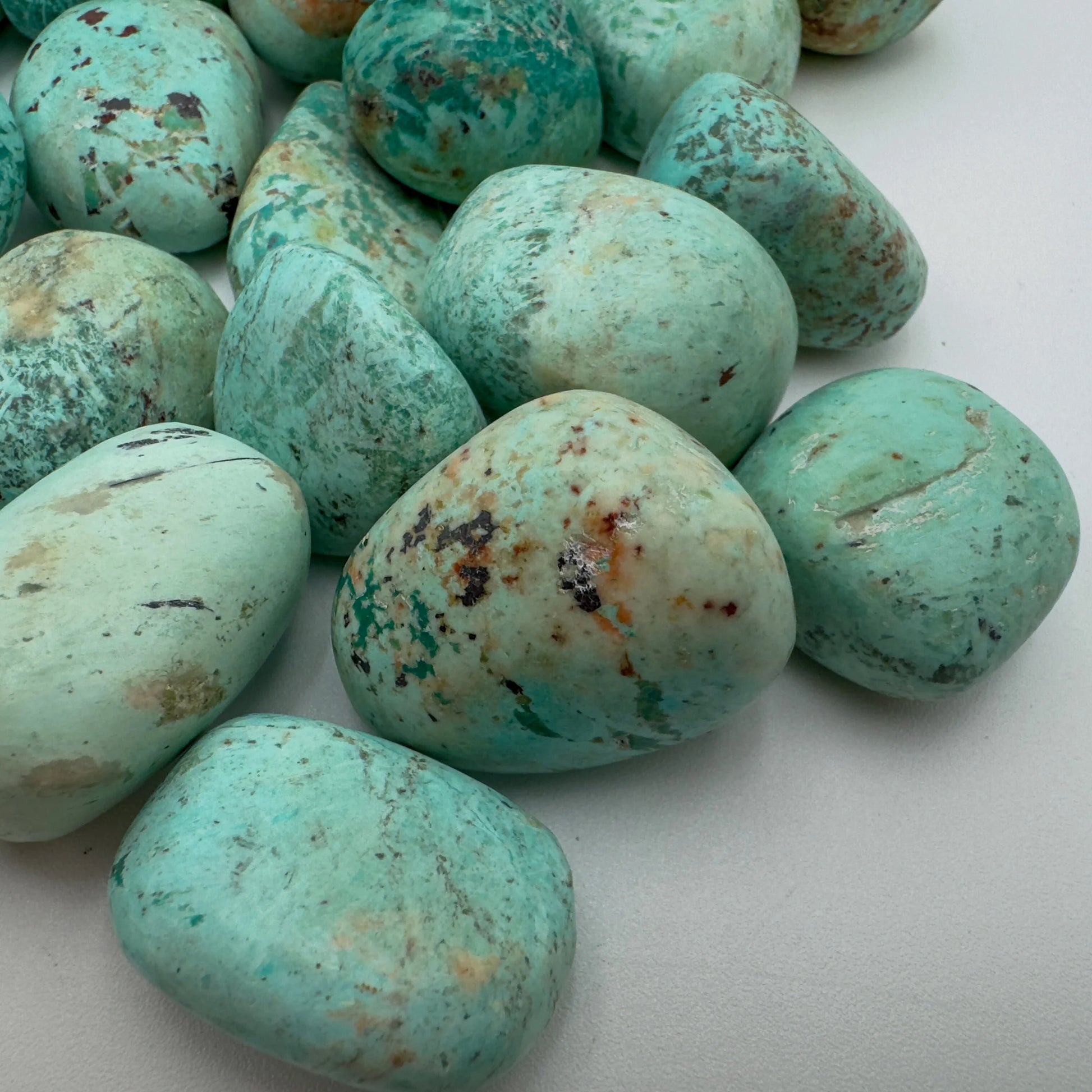 Edge-on view of Chrysocolla tumbled stone, showing subtle veining.
