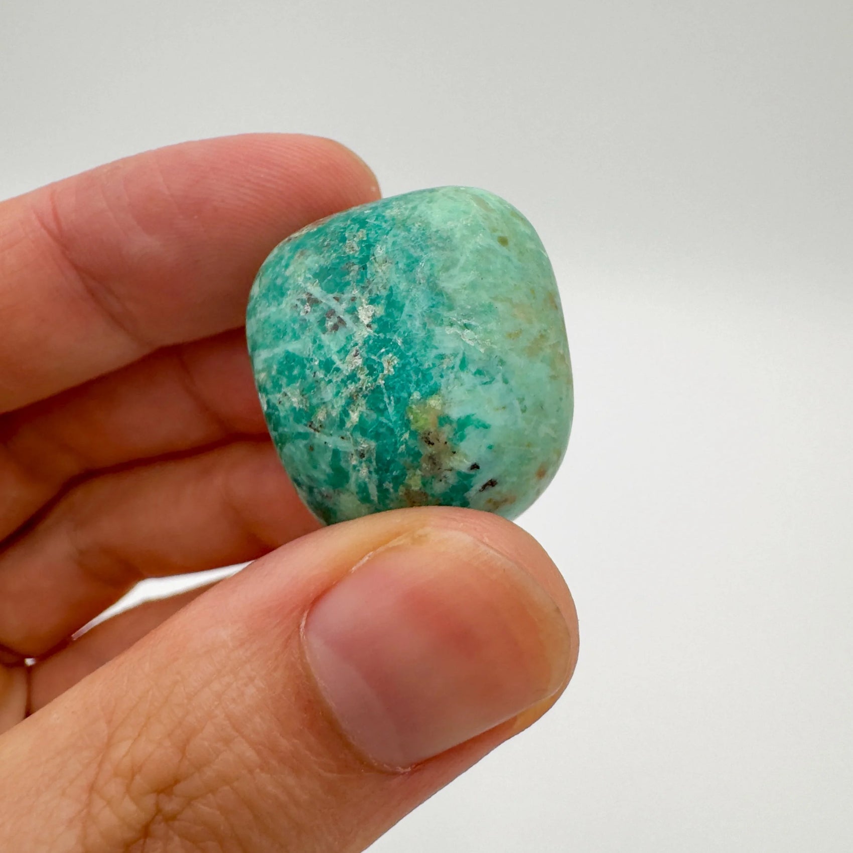 Lifestyle view of a Chrysocolla tumbled stone to support Emotional Healing, sourced from Arequipa, Peru.