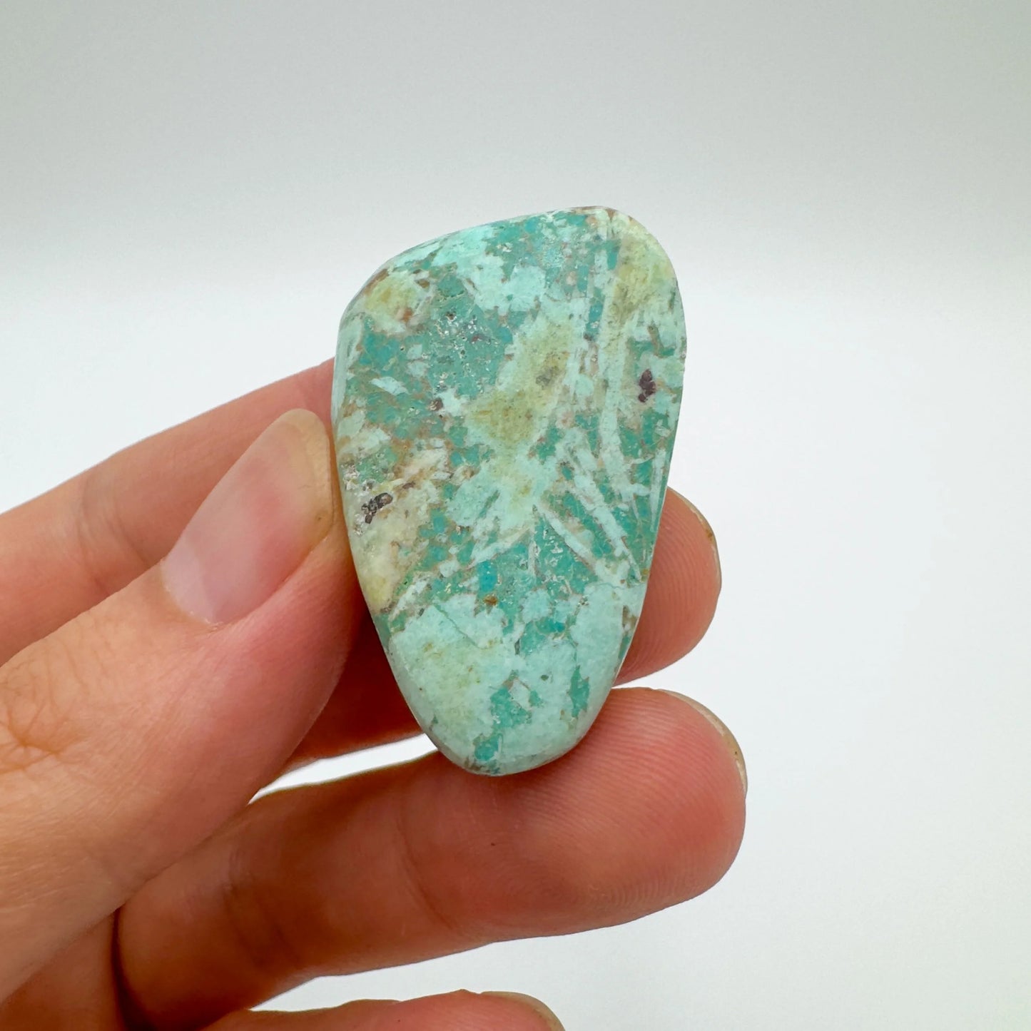 Lifestyle still of Chrysocolla tumbled stone, often kept for Emotional Healing, with character of the piece on display.