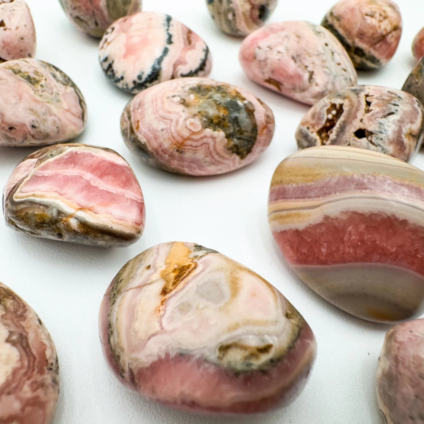 In-hand view of a single Rhodochrosite tumbled stone from Catamarca Province, Argentina.