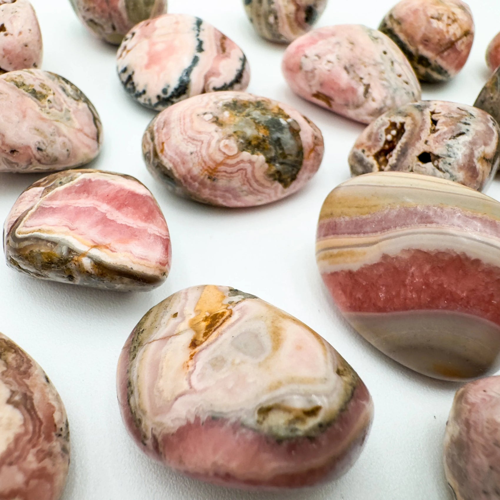 In-hand view of a single Rhodochrosite tumbled stone from Catamarca Province, Argentina.