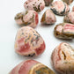 Daylight detail of Rhodochrosite tumbled stone, from Catamarca Province, Argentina, with surface texture in view.