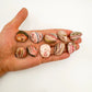 Detail shot of Grade A Rhodochrosite tumbled stone under natural light