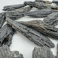 In-hand view of one Black Kyanite raw stone for scale, sourced from Brazil.
