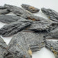 Grade a black kyanite raw held in hand for size reference
