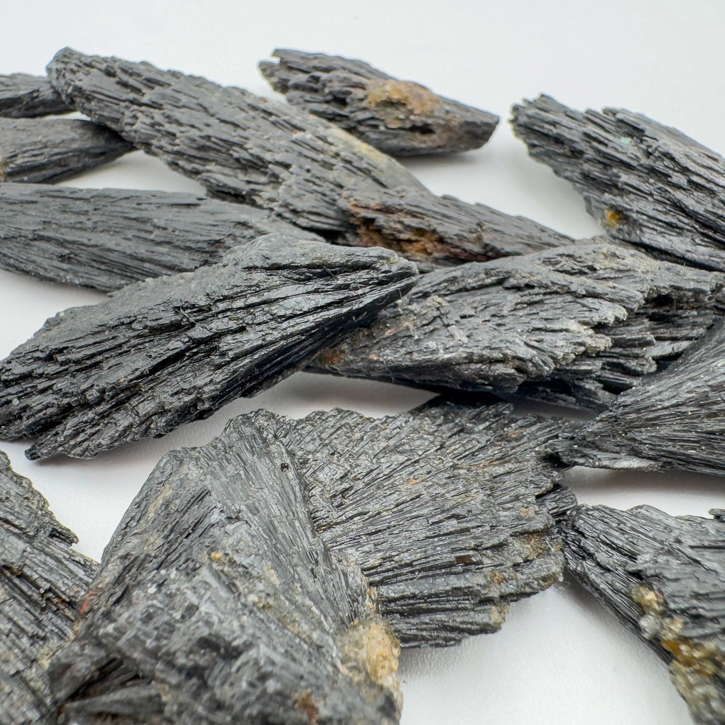 Grade a black kyanite raw held in hand for size reference