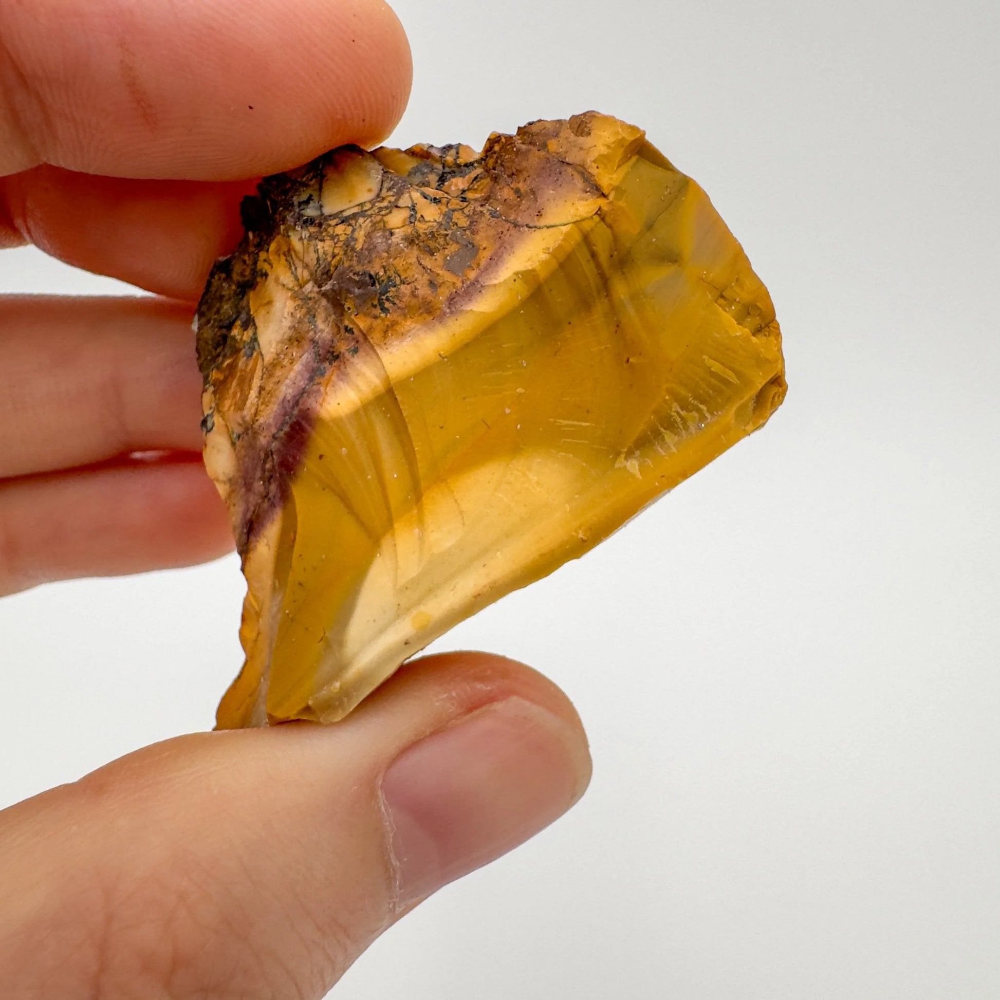 Hand-scale view of Mookaite stone, associated with Adventure, shown alongside the hand for scale.