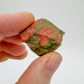 Holding an Unakite raw crystal, with hand-sized presence.