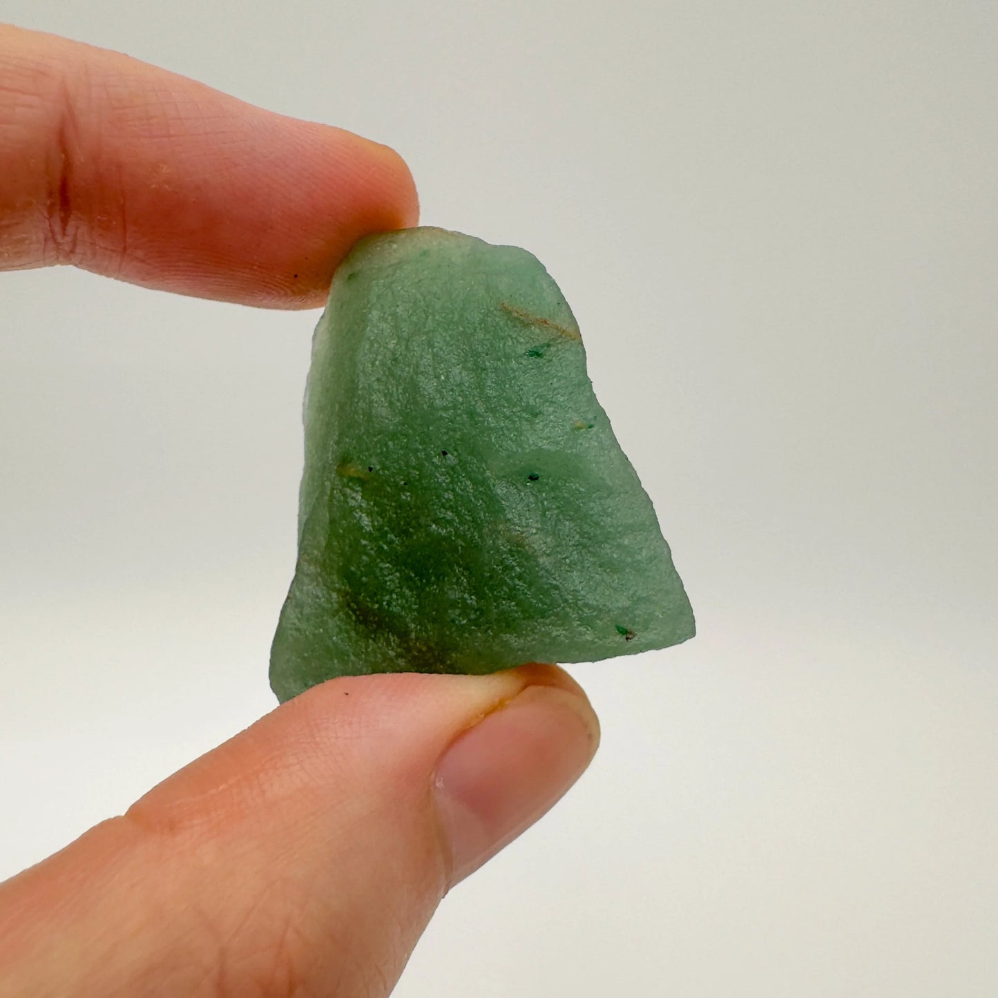 Hand-scale shot of a Aventurine raw stone held against natural backdrop, hand-selected from Minas Gerais, Brazil.