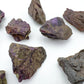 Lifestyle view of a Stichtite raw stone held against natural backdrop, hand-selected from Mpumalanga, South Africa.