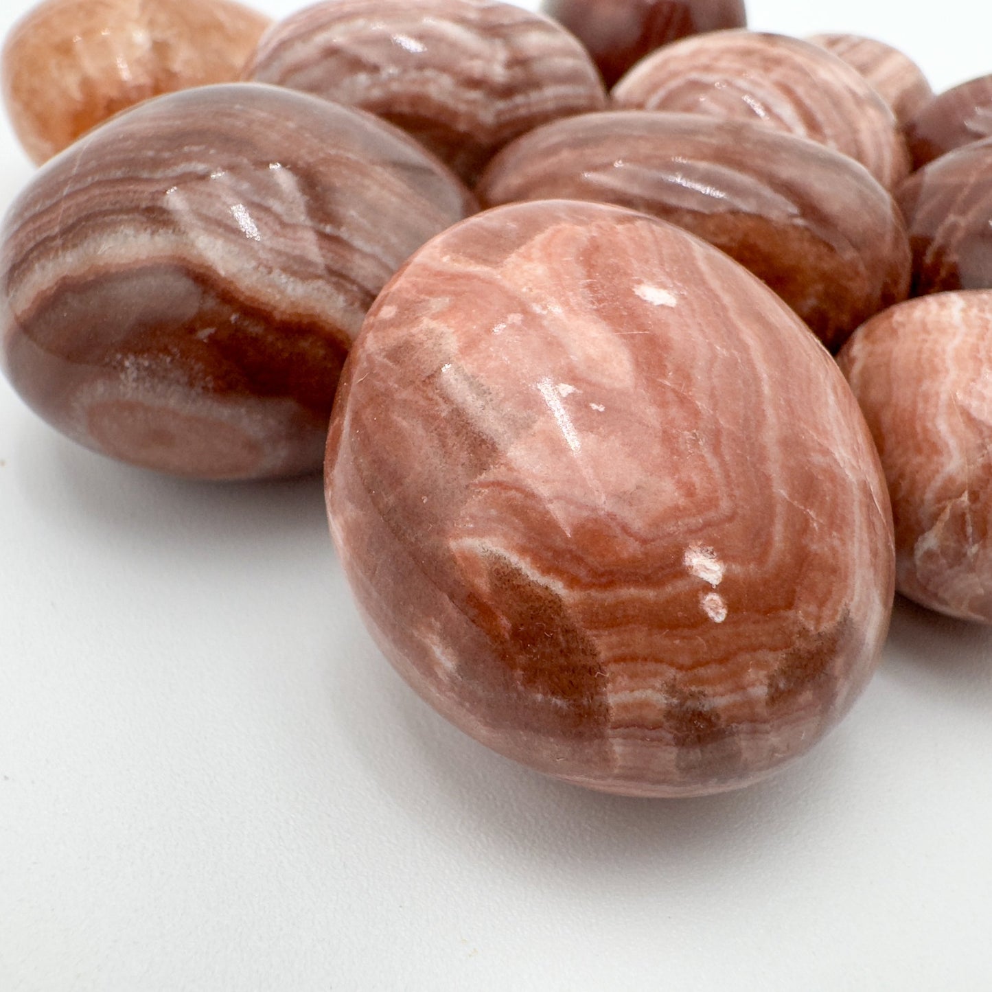 Size comparison with a single Red Aragonite tumbled stone Peru-sourced.