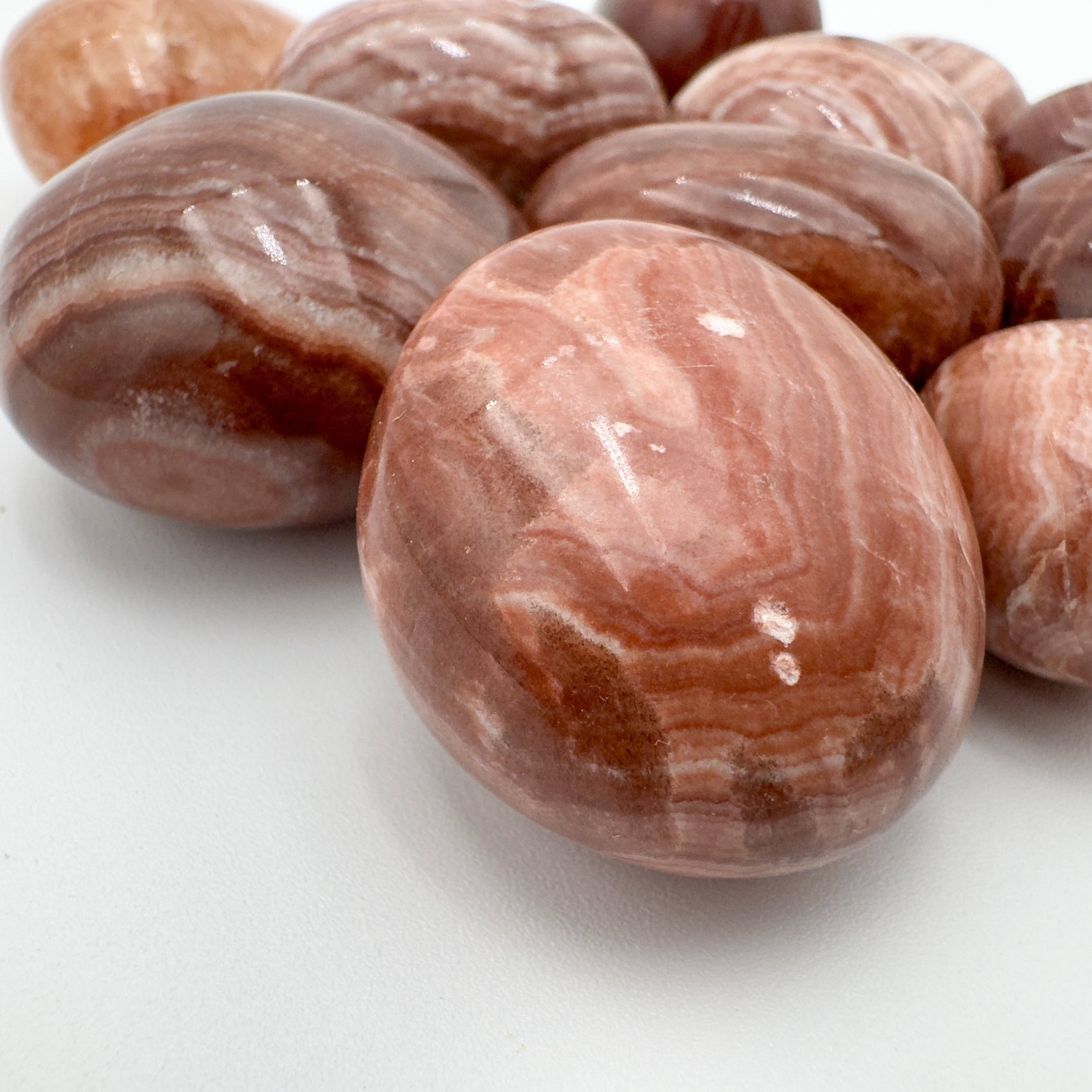 Size comparison with a single Red Aragonite tumbled stone Peru-sourced.