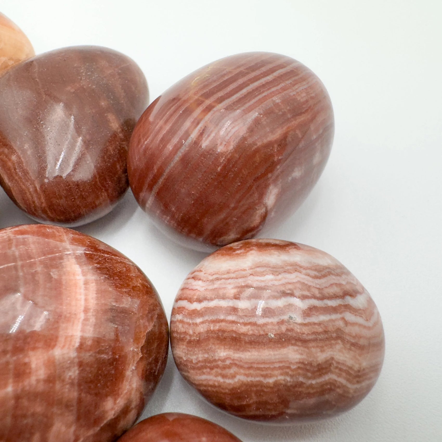 Looking down on Red Aragonite tumbled stone, sourced from Junín, Peru, showing translucent edges.