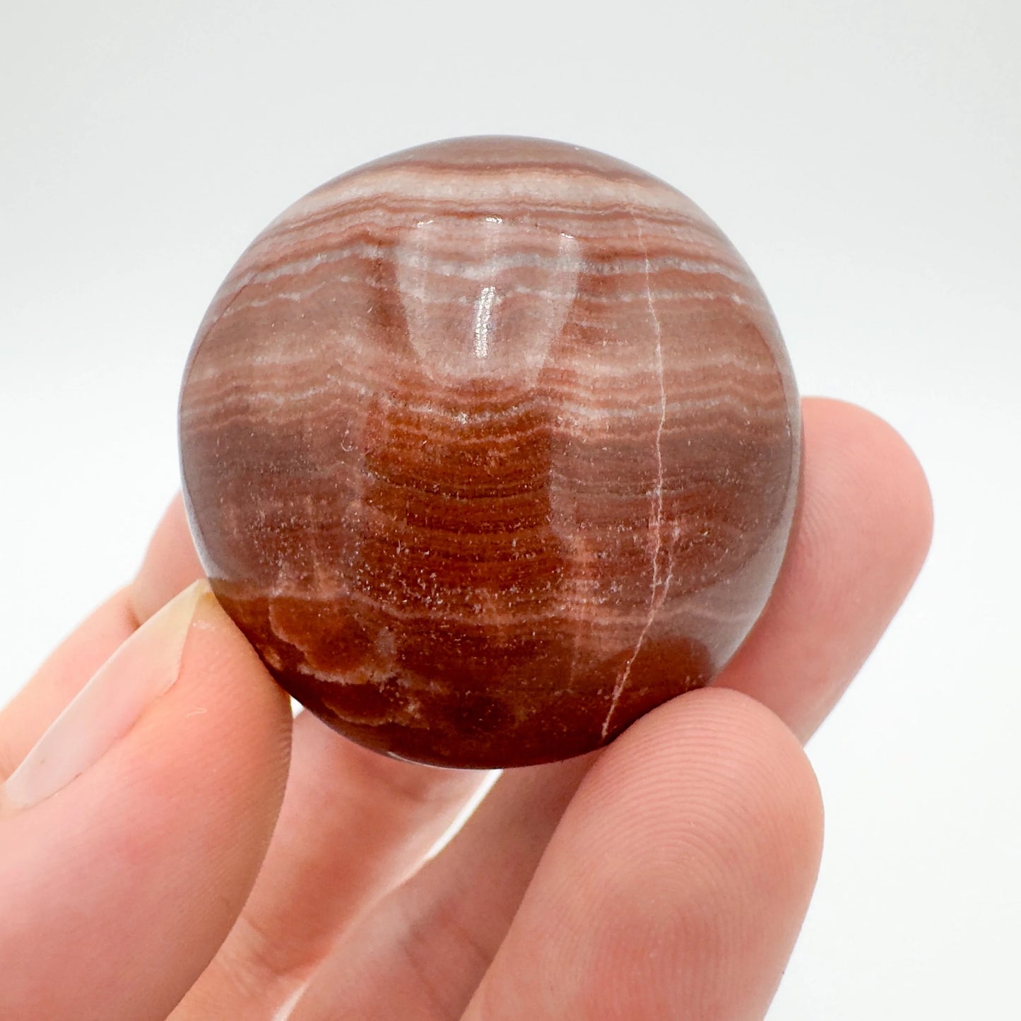 Detail shot of Grade AAA Red Aragonite tumbled stone under natural light