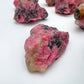 Sideways view of Rhodonite raw stone, showing natural form, hand-selected from Masvingo, Zimbabwe.