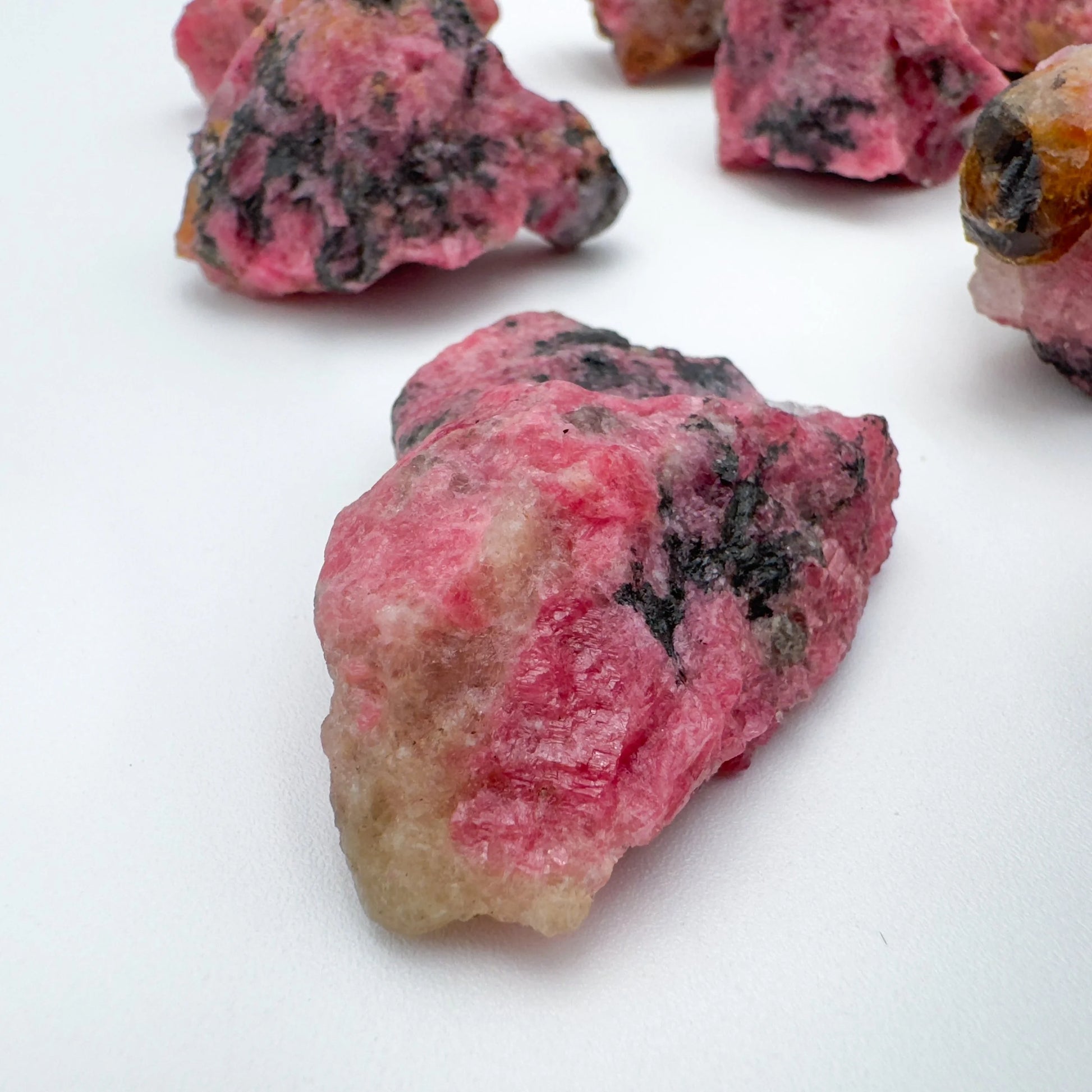 Sideways view of Rhodonite raw stone, showing natural form, hand-selected from Masvingo, Zimbabwe.