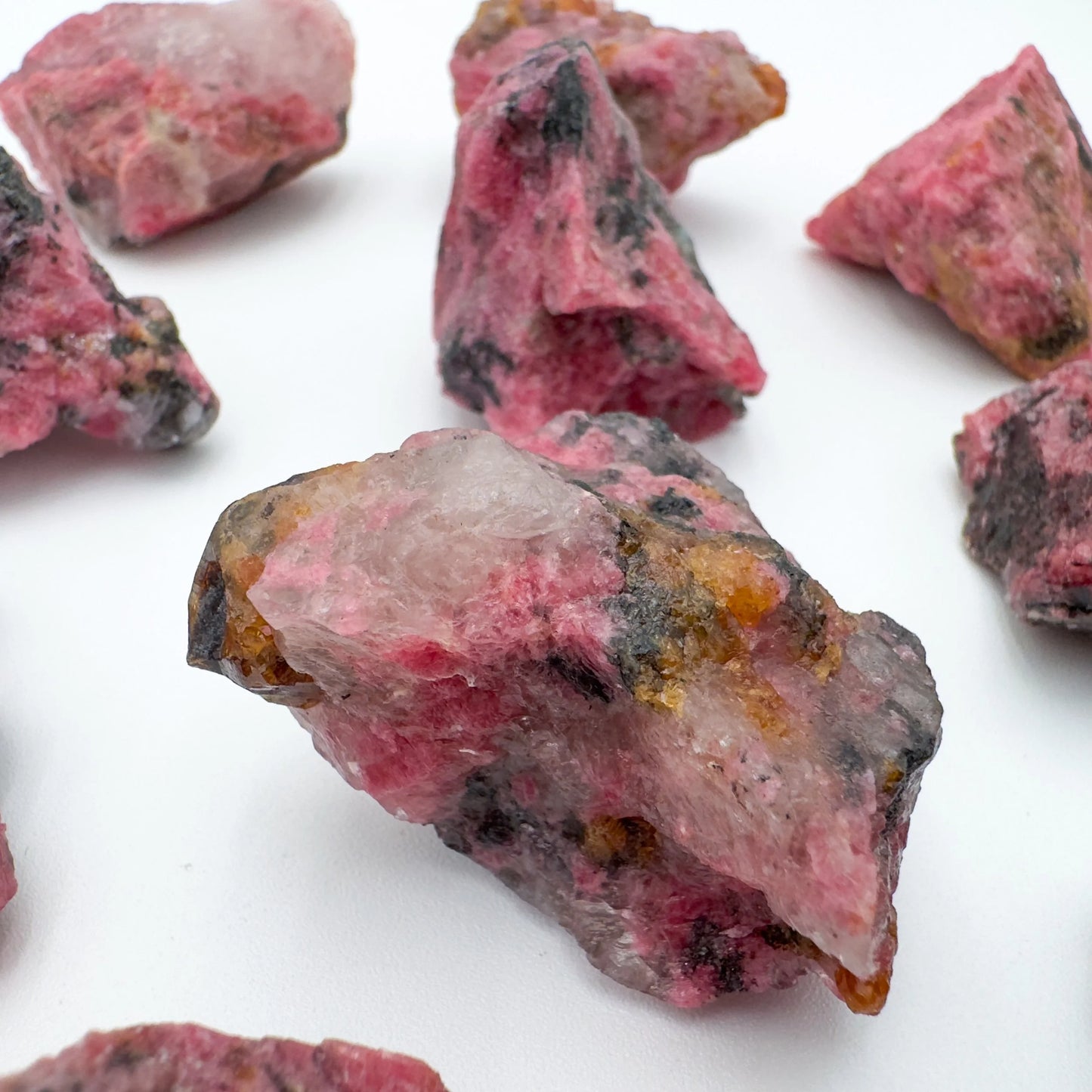Reverse side of Grade AA pink Rhodonite raw stone, showing natural banding, sourced from Zimbabwe.