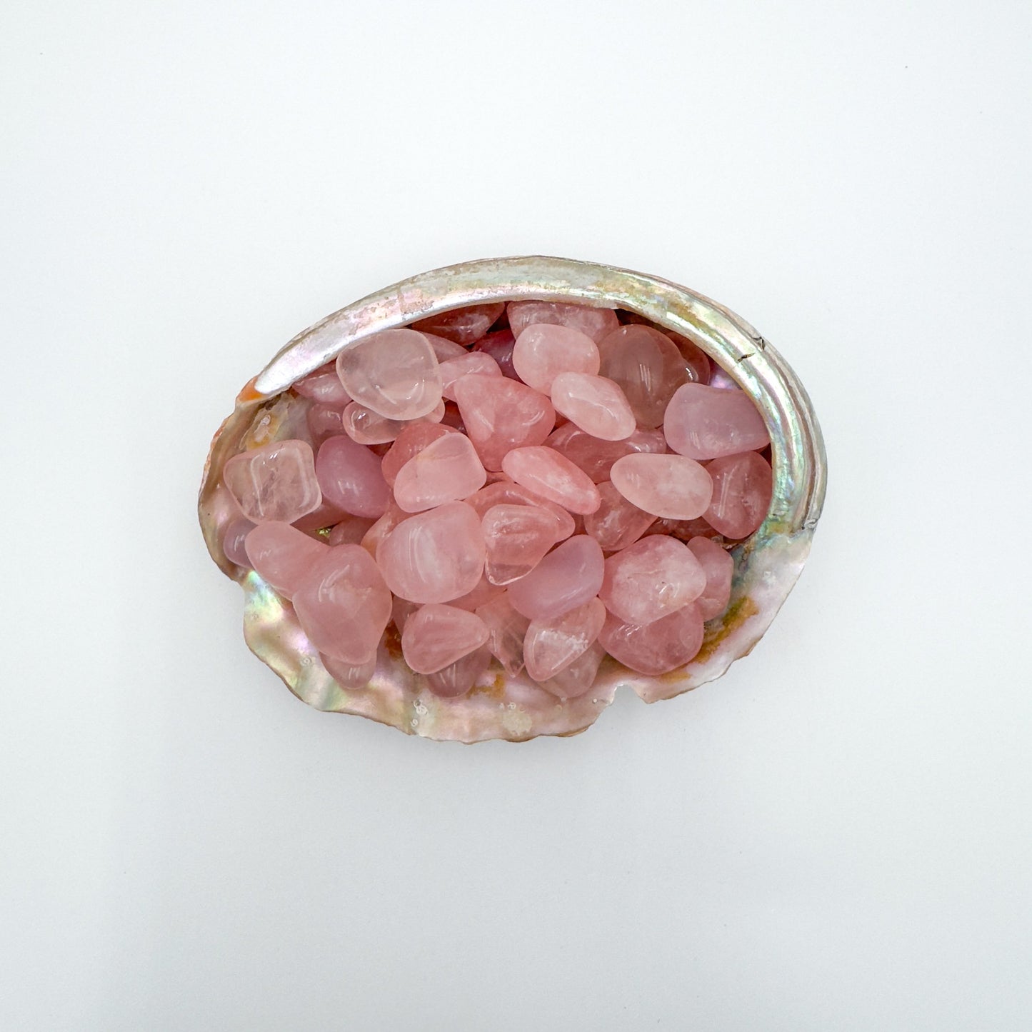 Close detail of pink Rose Quartz tumbled stone, associated with Love, showing natural texture.