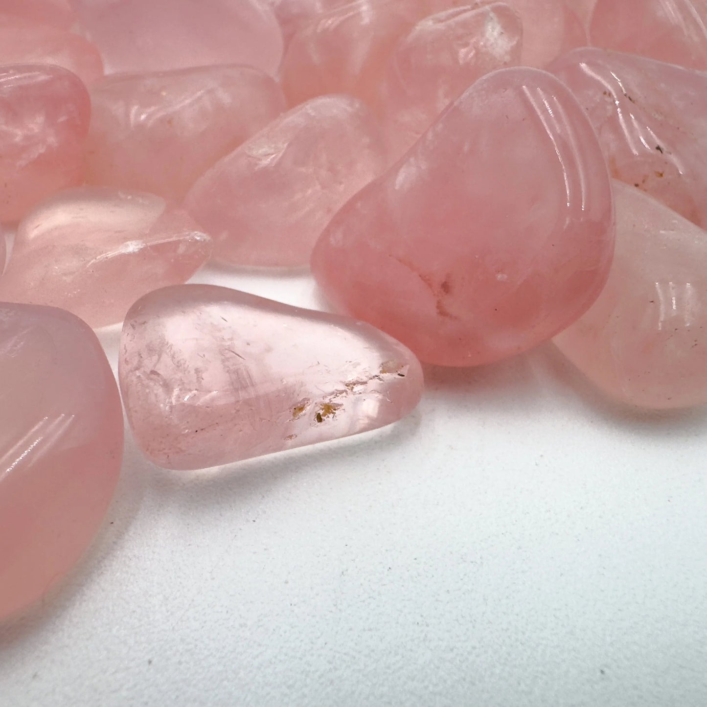Edge-on view of Rose Quartz tumbled stone, turned to for Love, showing translucent edges.