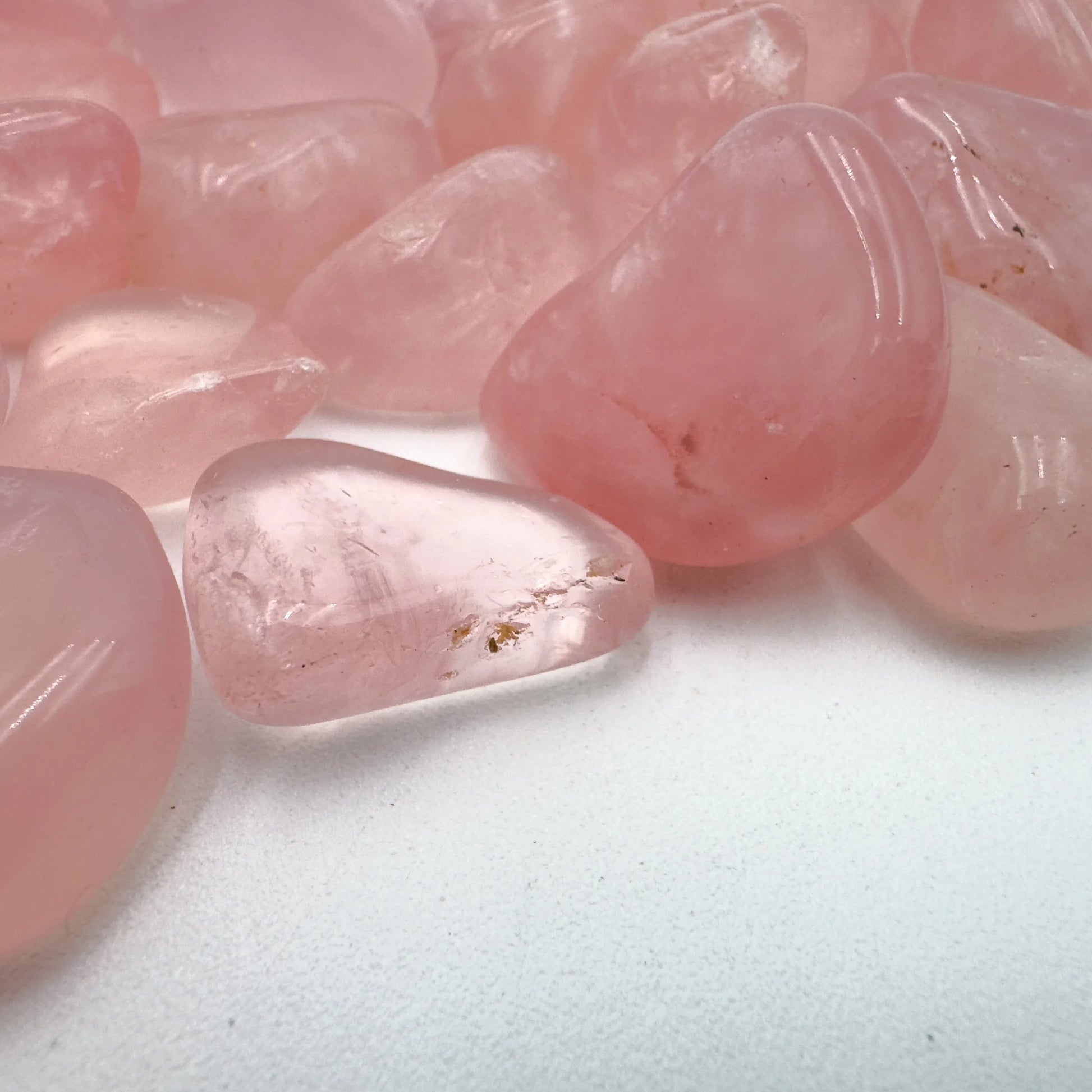 Edge-on view of Rose Quartz tumbled stone, turned to for Love, showing translucent edges.