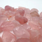 In-hand view of a single Rose Quartz tumbled stone sourced from Brazil.