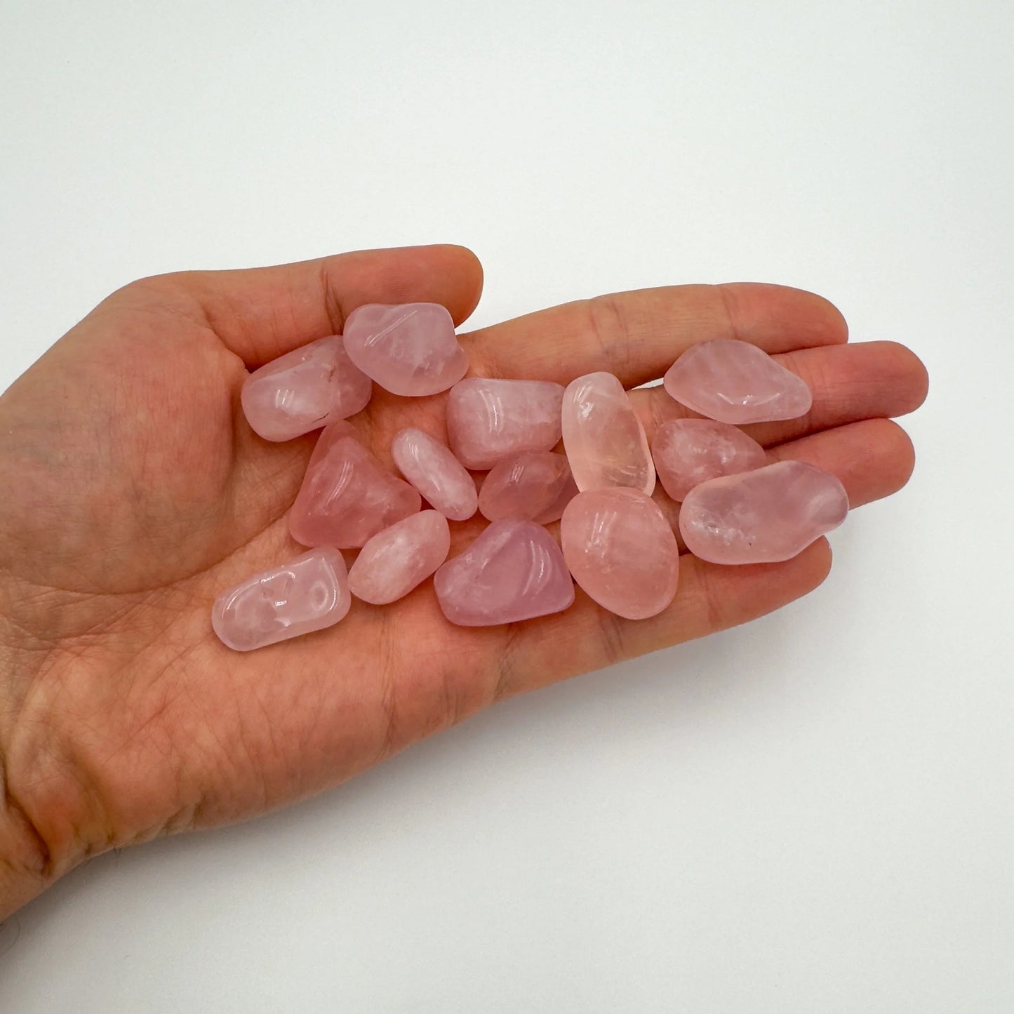 Styled with natural light Rose Quartz tumbled stone, linked to Stress Relief, shown at hand scale.