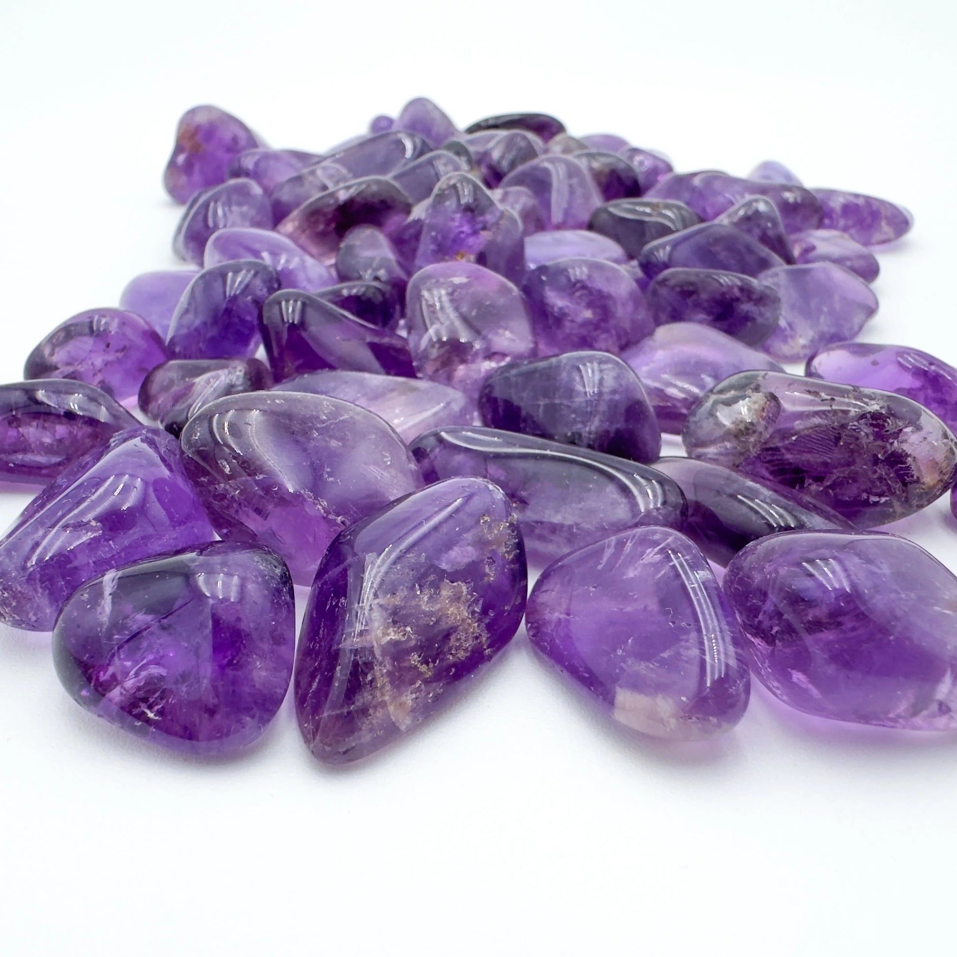 Scale comparison of Amethyst tumbled stone, from Rio Grande do Sul, Brazil, shown alongside the hand for scale.