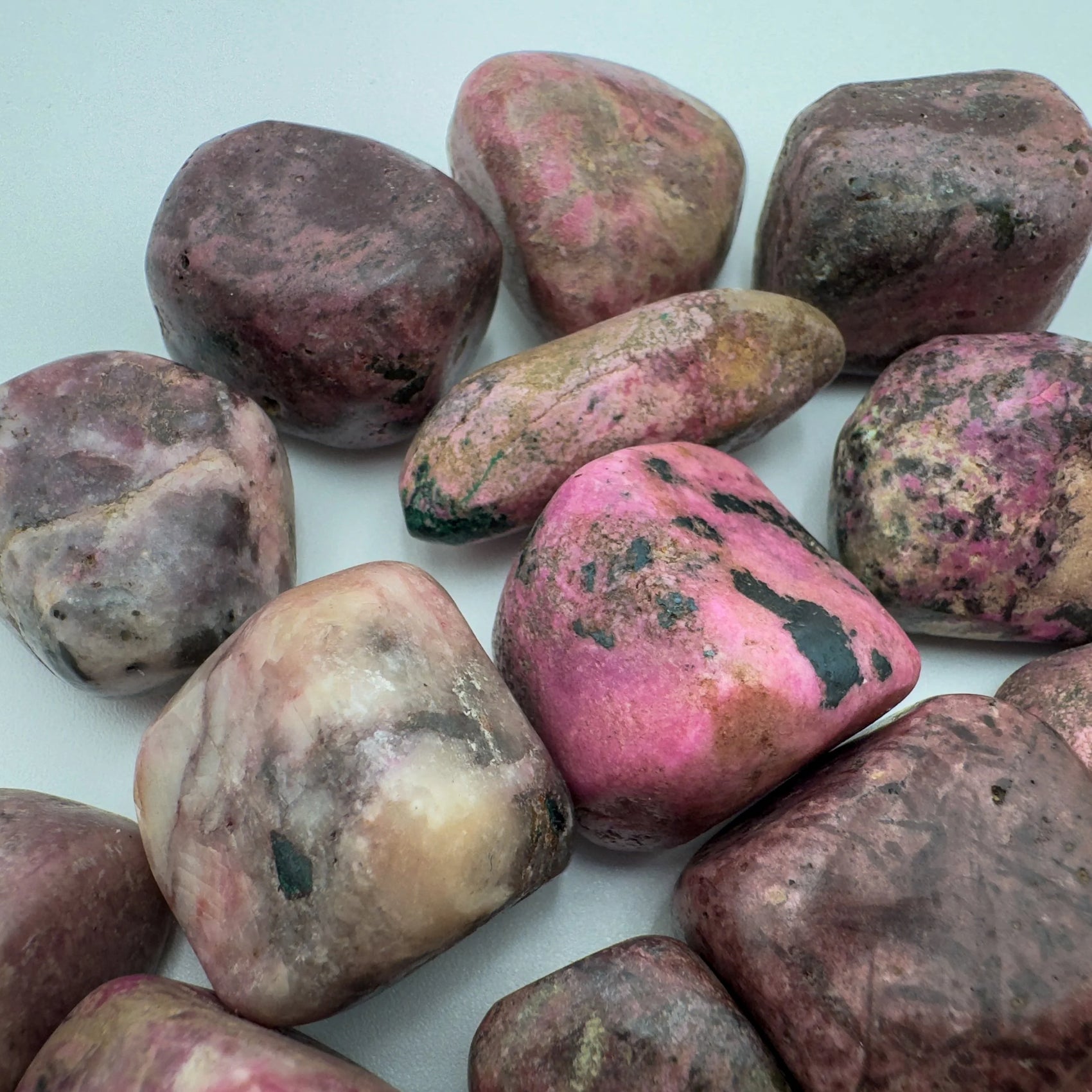 Top angle of Grade A Cobalt Calcite tumbled stone, hand-selected from Haut-Lomami, Democratic Republic of the Congo, kept near.