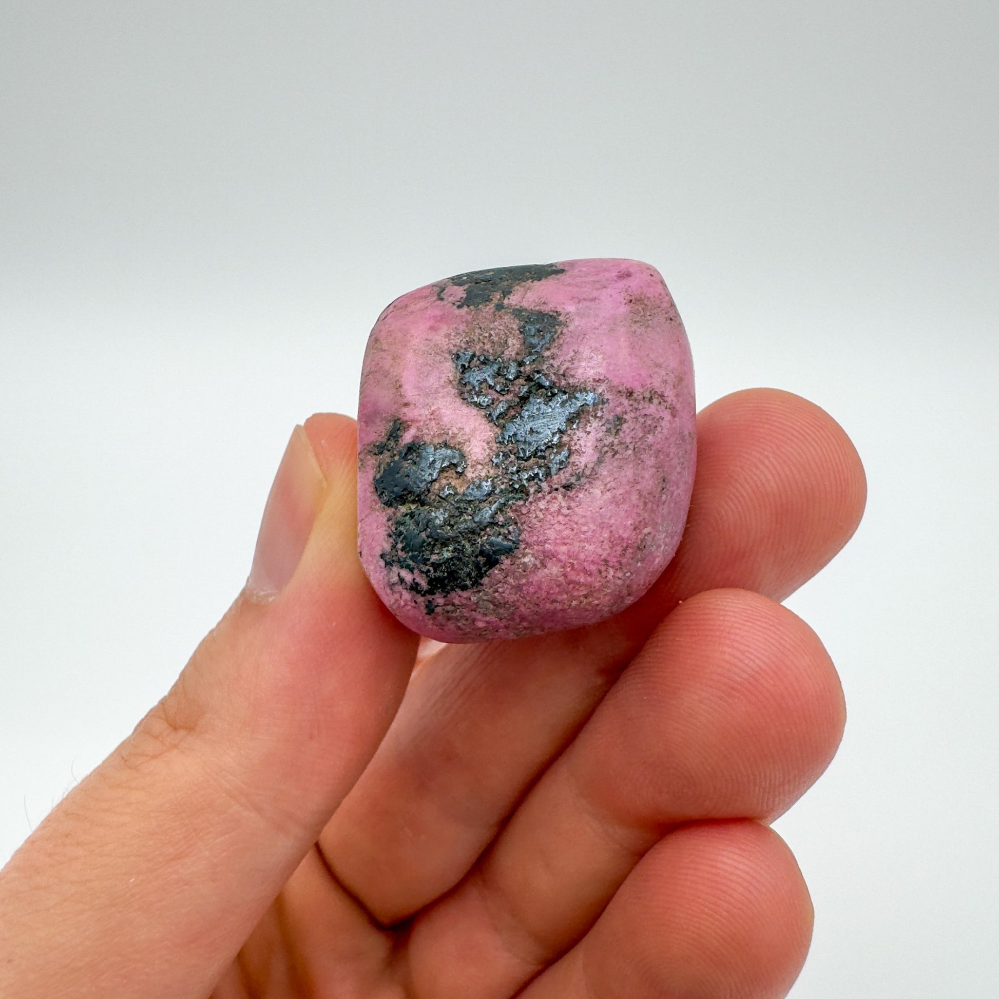 Palm-scale view of one Cobalt Calcite tumbled stone for scale, hand-selected from Haut-Lomami, Democratic Republic of the Congo.