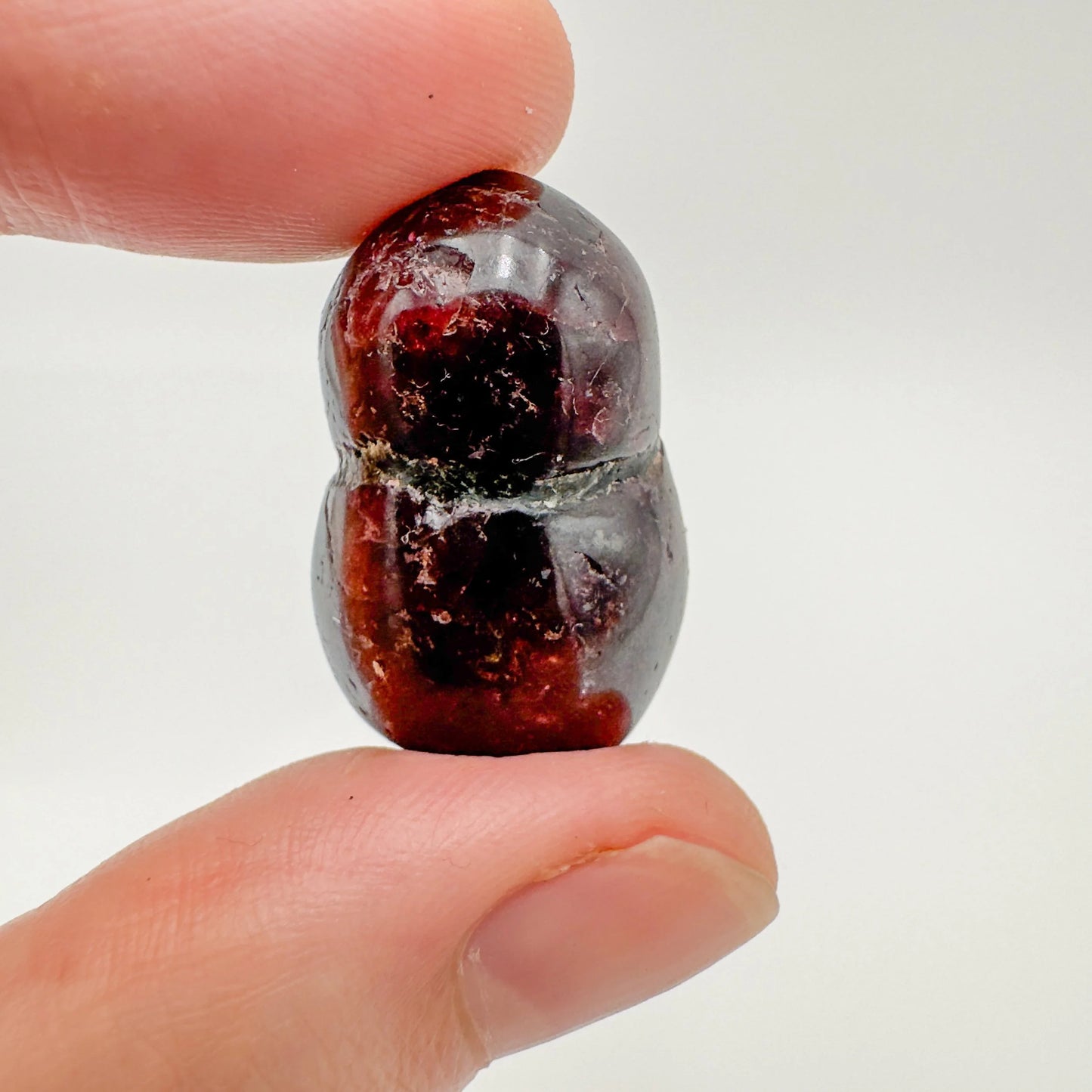 Three-quarter view of Garnet tumbled stone, shown in a calm studio setting.