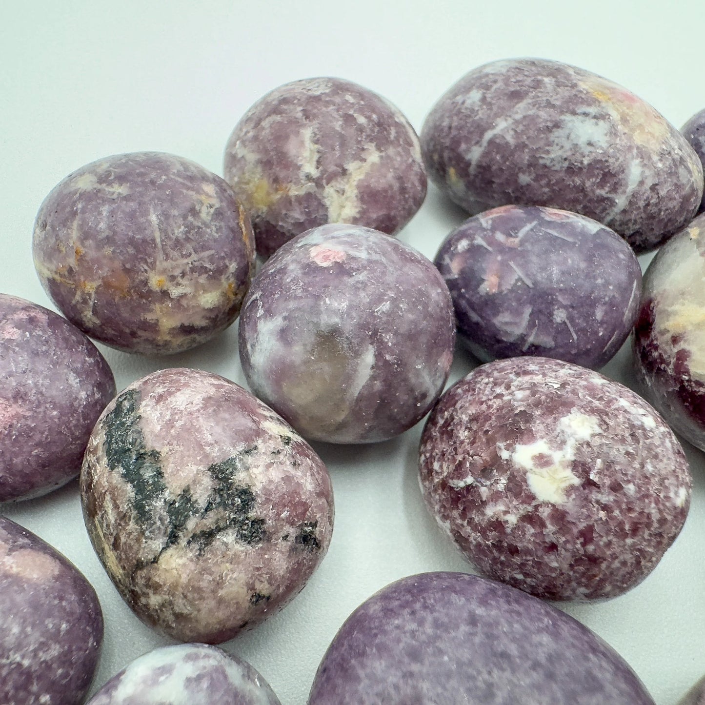 Underside detail of purple Lepidolite tumbled stone, linked to Stress Relief, showing characteristic finish.
