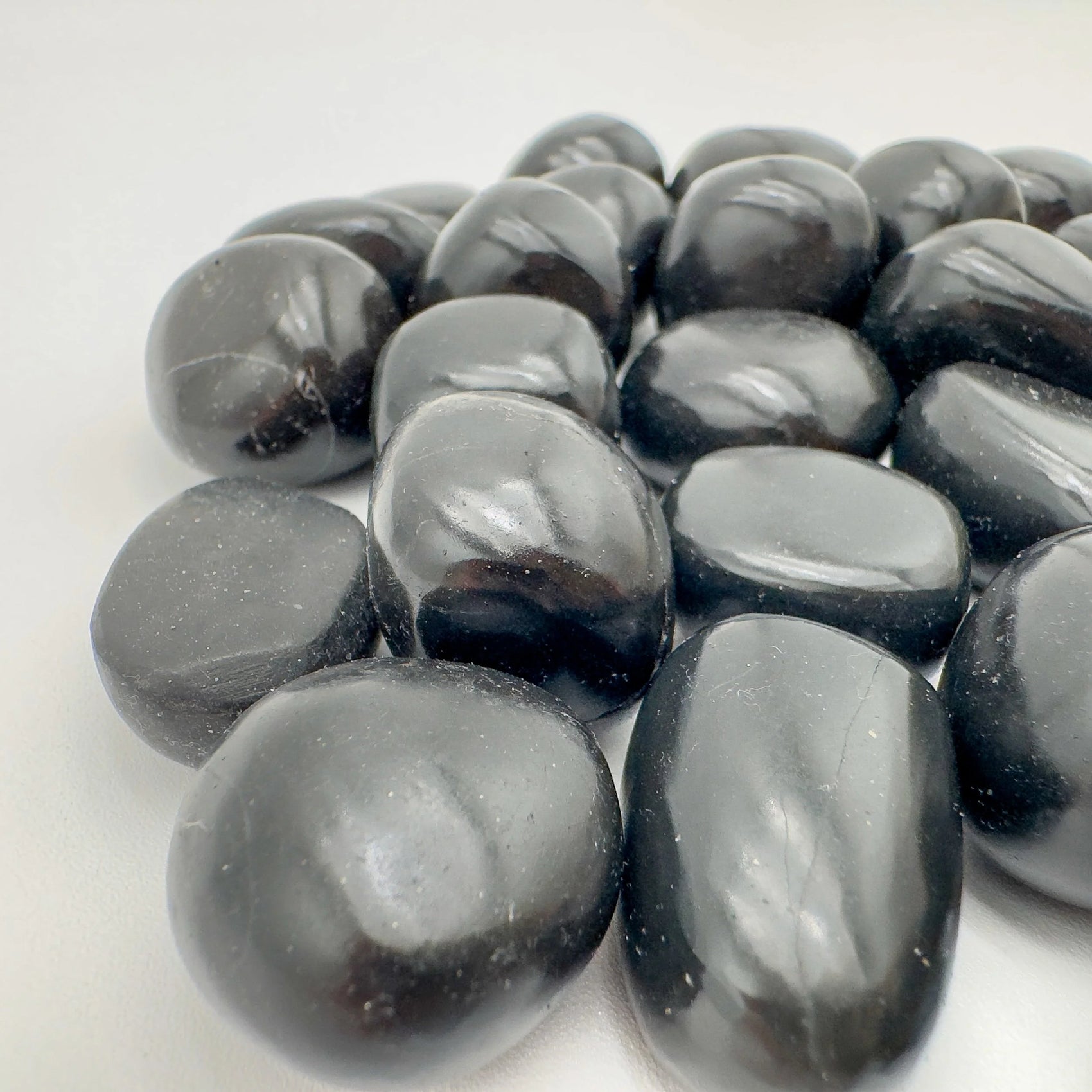 Palm-scale view of one Black Onyx tumbled stone for scale, Peru-sourced, hand-selected from Ancash, Peru.