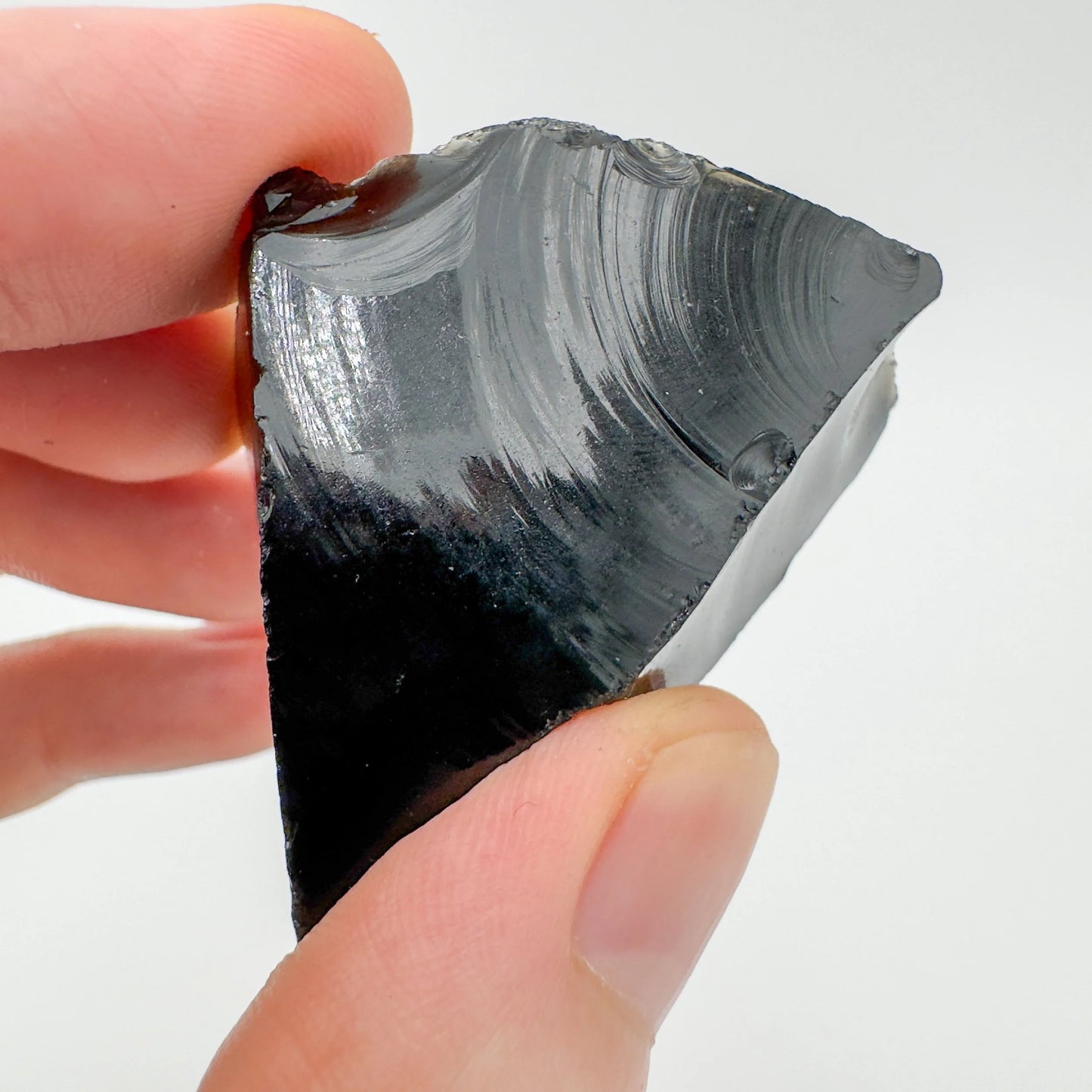 Palm-scale view of a single Black Obsidian raw stone sourced from Argentina.